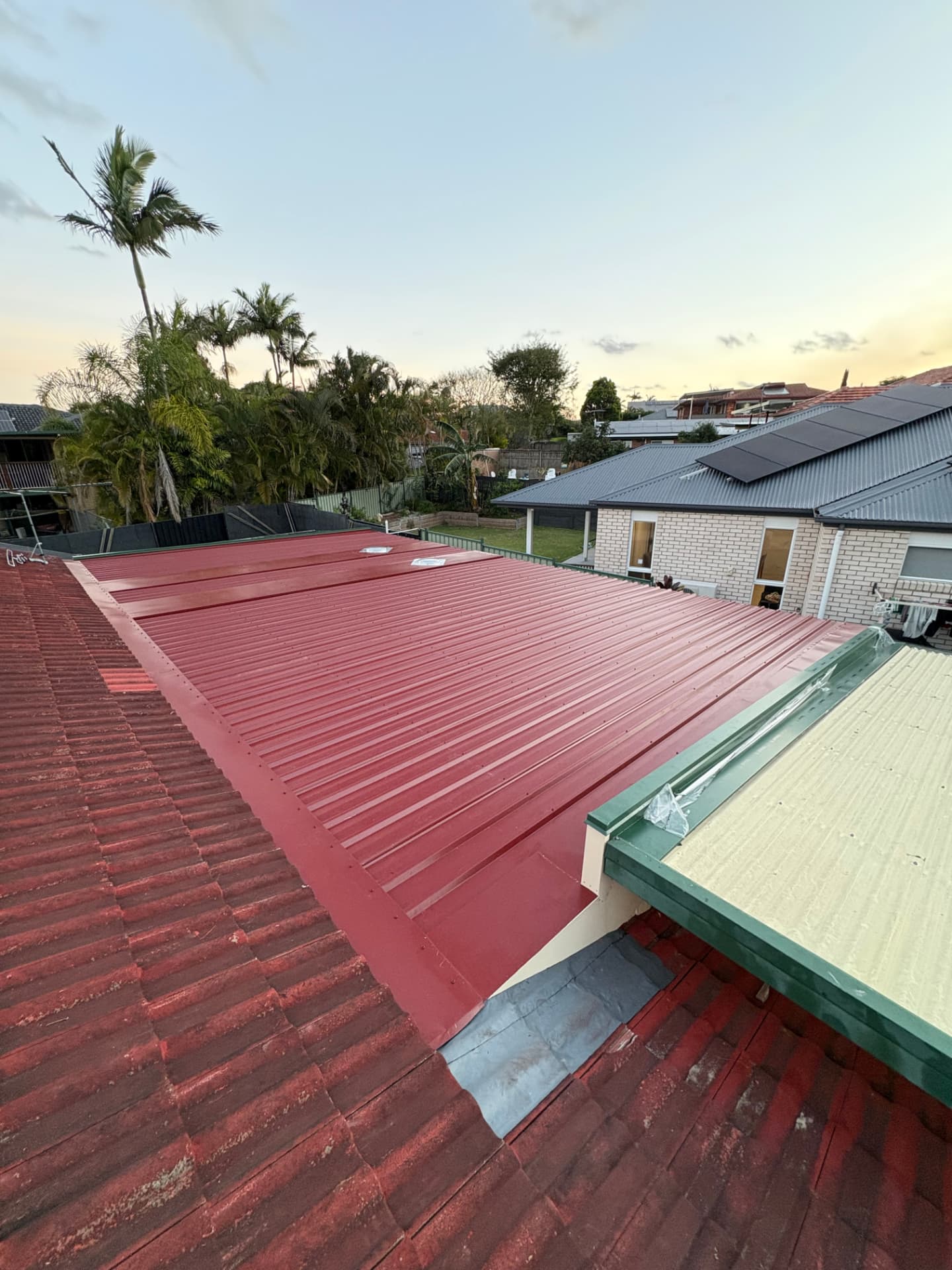 Completed metal roof conversion lapping into the tiled roof at dusk
