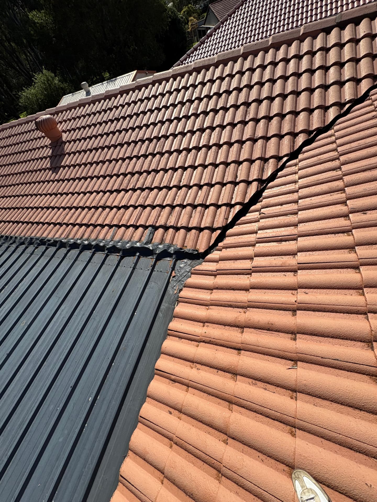 Junction between a tiled roof and metal fly-over roof sheeting with makeshift sealing